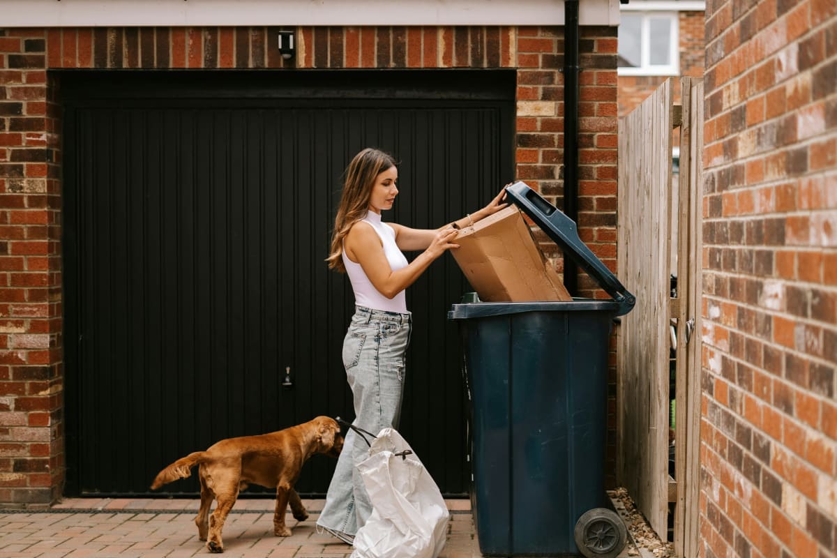Taking out the trash by the garage with the dog