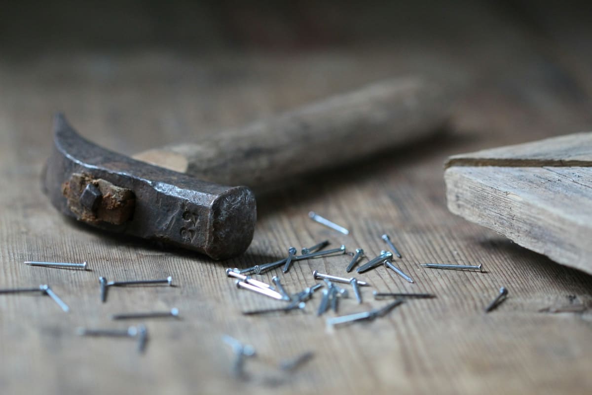 Claw hammer and nails on a worn plank