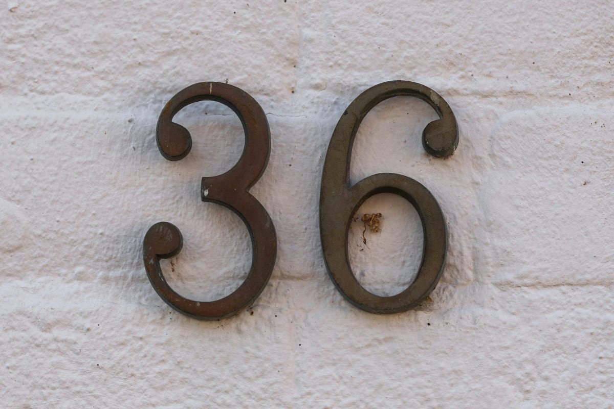 Bronze house numbers on a white brick wall
