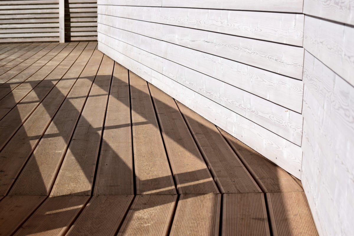 Hardwood deck along a white-sided wall