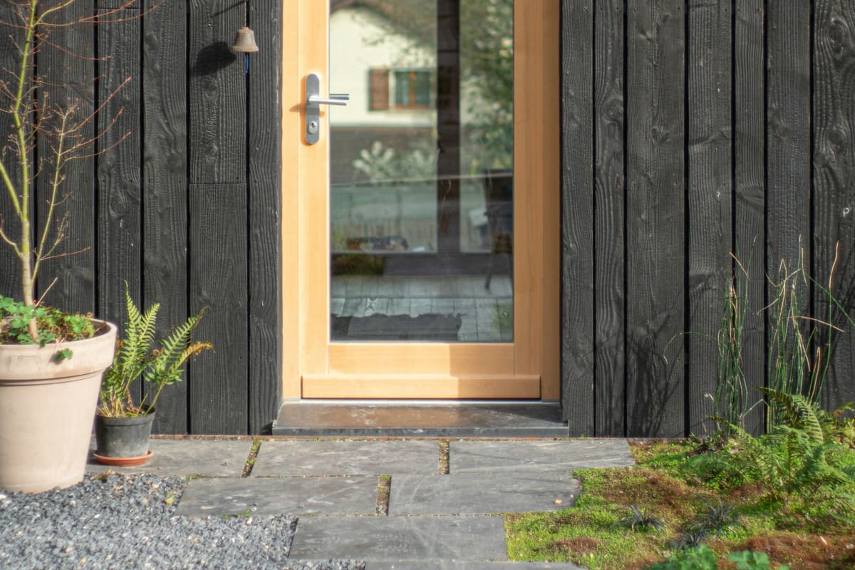Wood-framed glass door on a dark-sided home