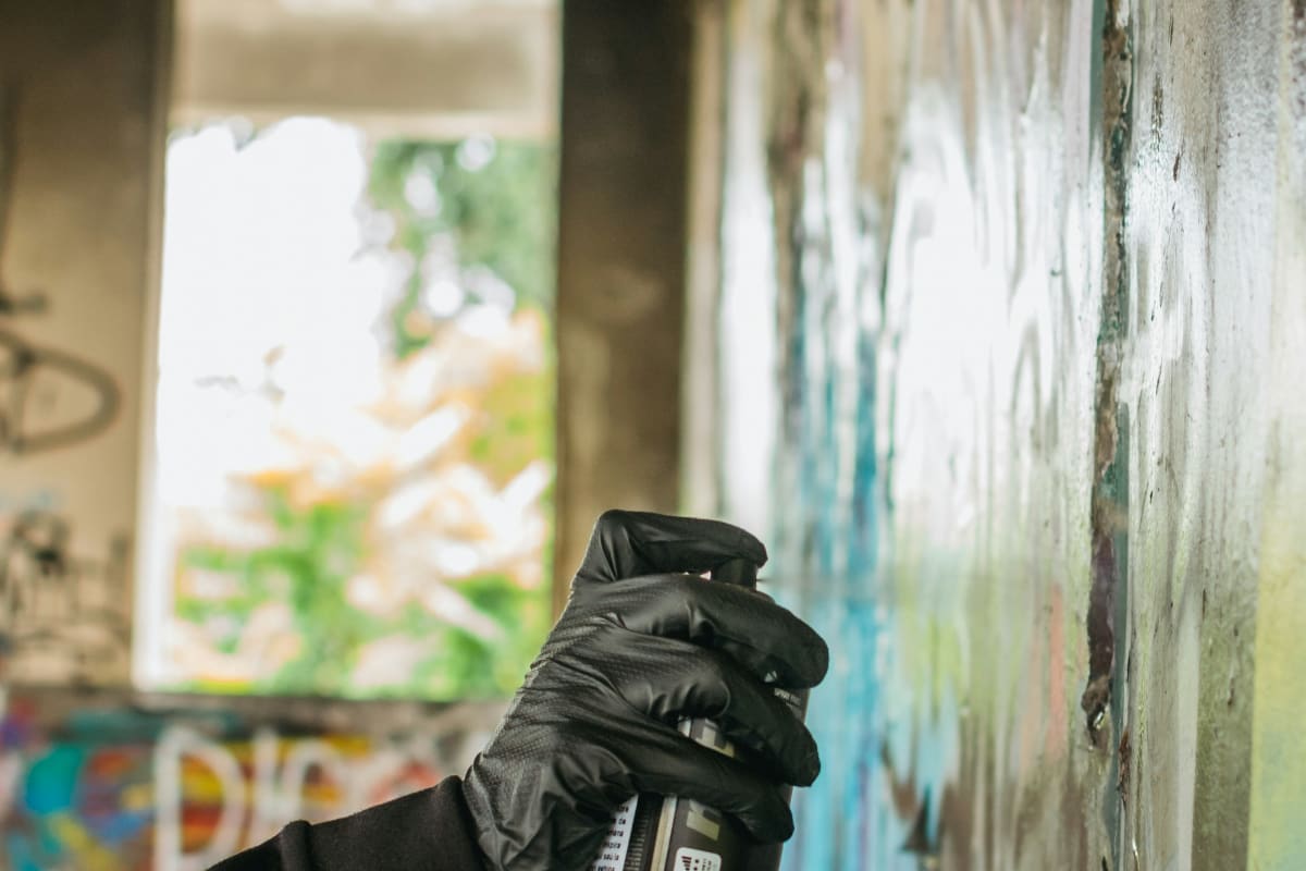 Spray painting a wall in a gloved hand