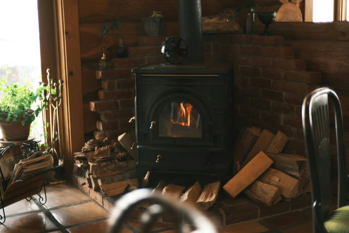 Wood stove in a cabin with split wood beside it