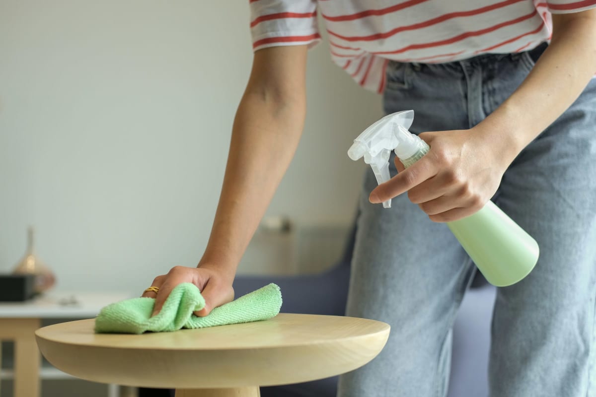 Wiping a table with spray cleaner