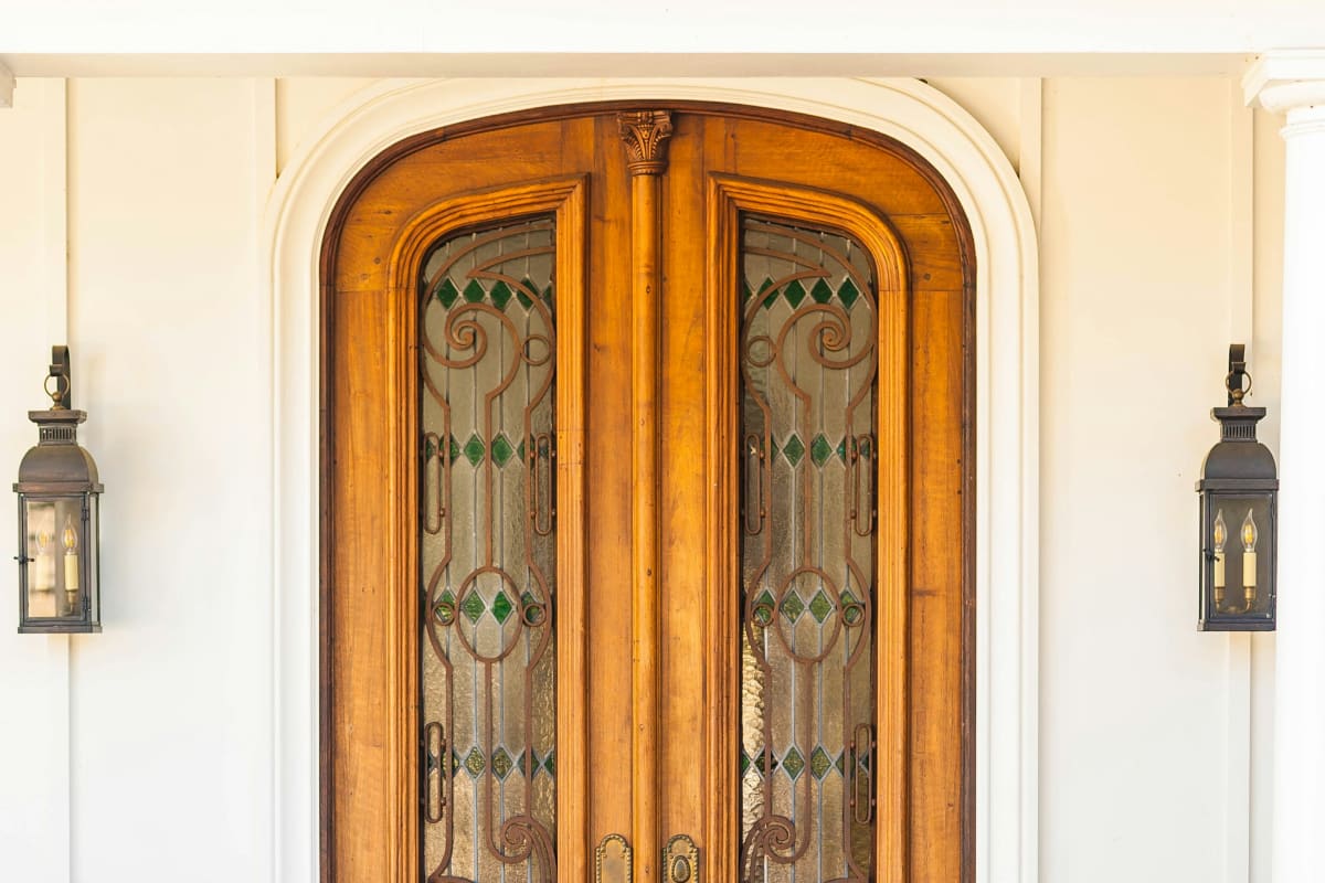 Carved wood double front door with decorative glass, flanked by pumpkins