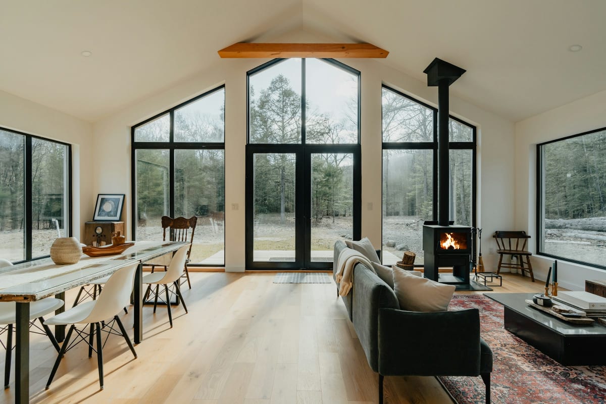 Vaulted living room with tall black-framed windows and a wood stove
