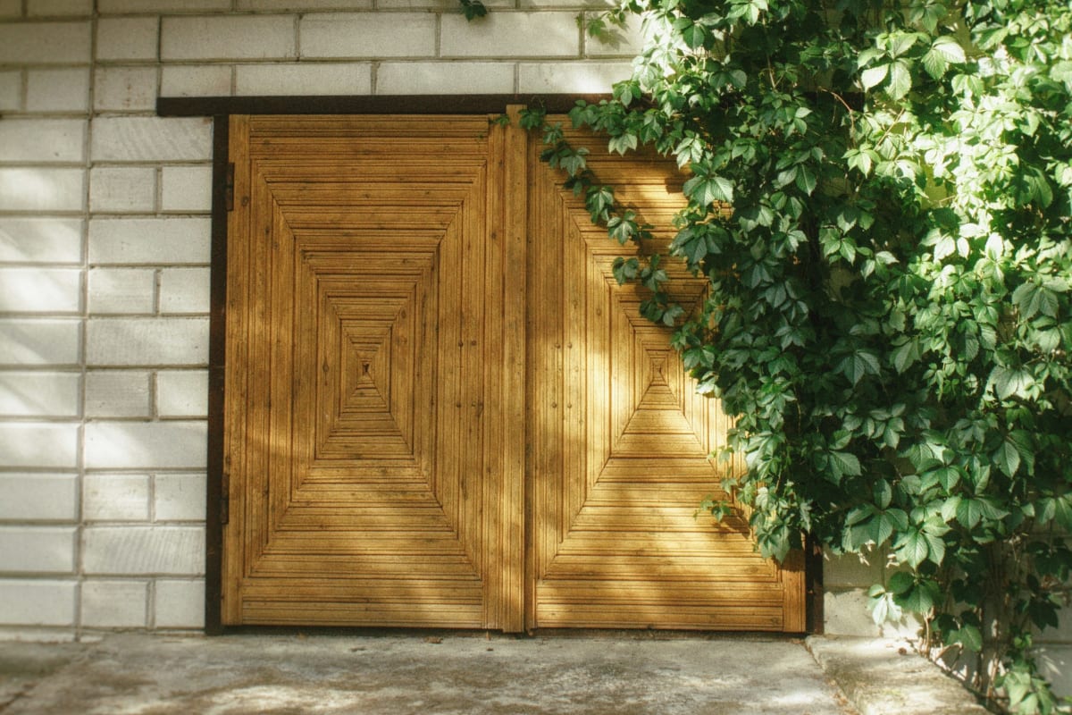 Wood carriage garage door under climbing vines