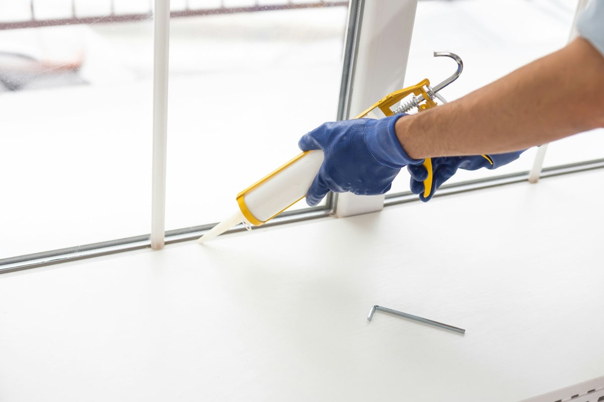 Sealing along a window frame with a caulk gun