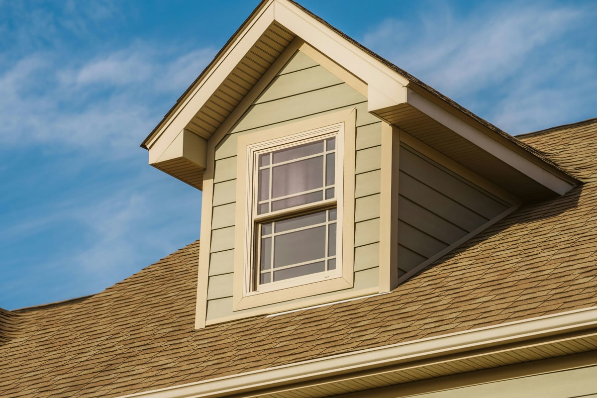 Shingle roof around a dormer with sage green siding