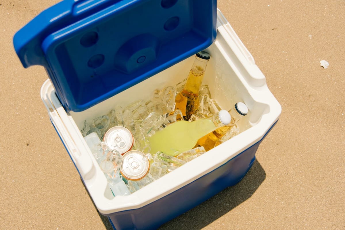 Cooler packed with ice and drinks on the sand