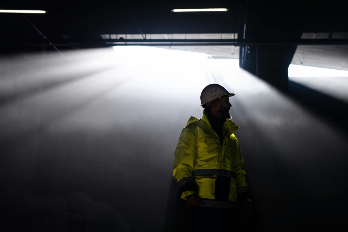 Worker in a hard hat lit by work lights