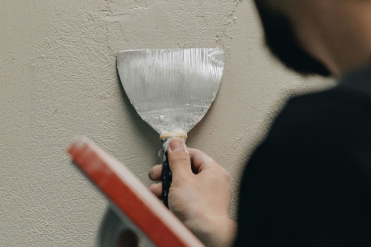 Scraping a wall with a wide putty knife