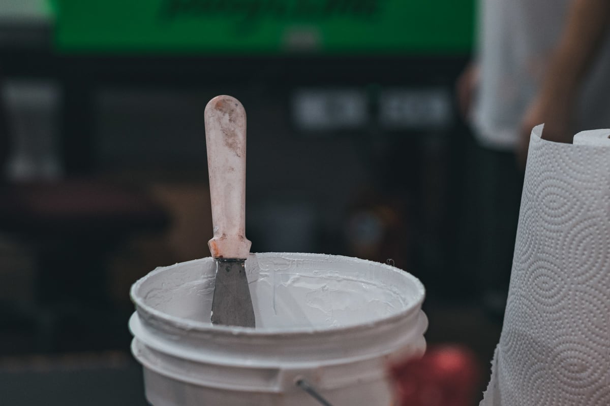 Putty knife in a bucket of compound
