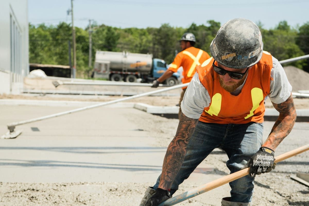 Worker spreading fresh concrete on a job site