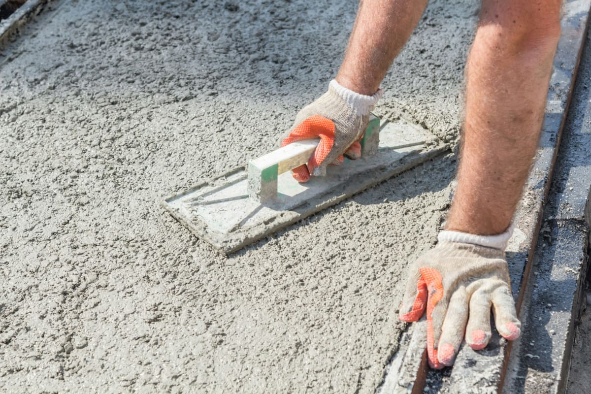 Gloved hand finishing fresh concrete with a float