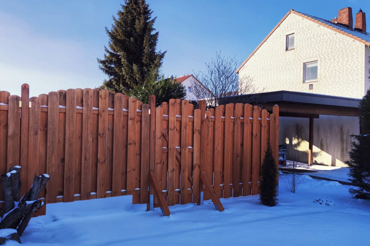 Stained fence around a snowy yard