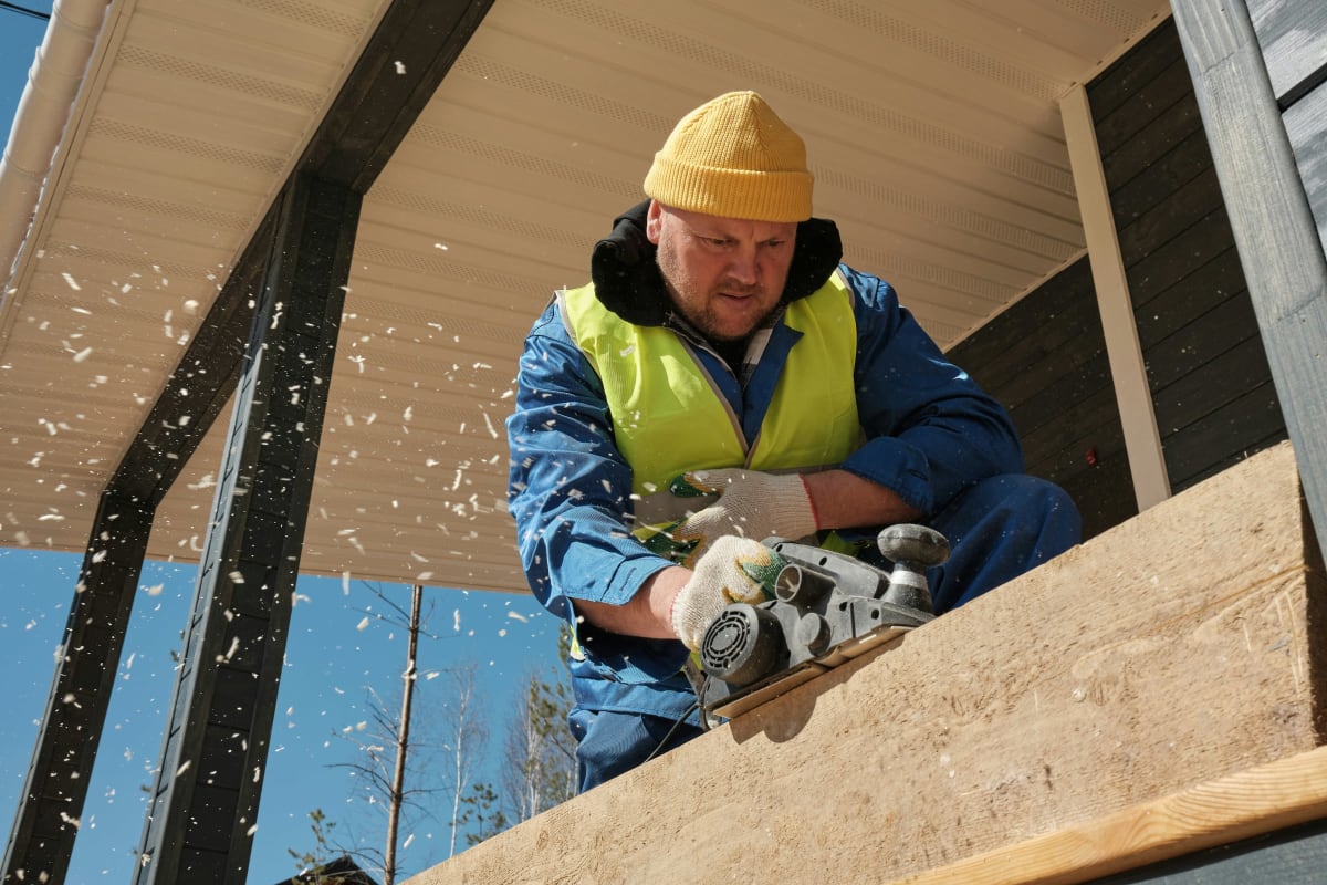 Carpenter cutting a board on a porch