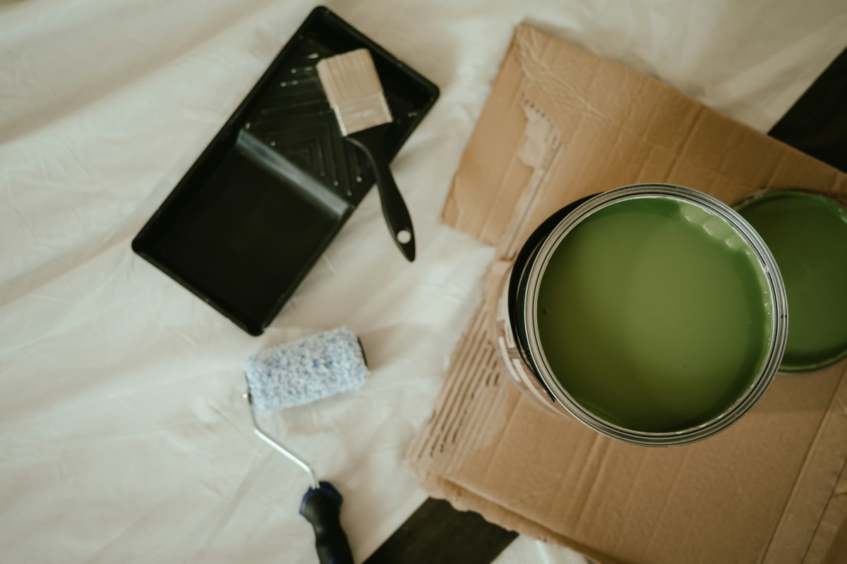Can of green paint with a roller and tray