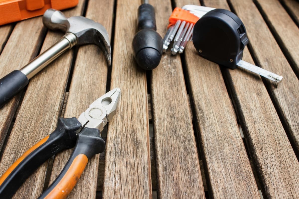Hammer, pliers and a tape measure on a wood deck