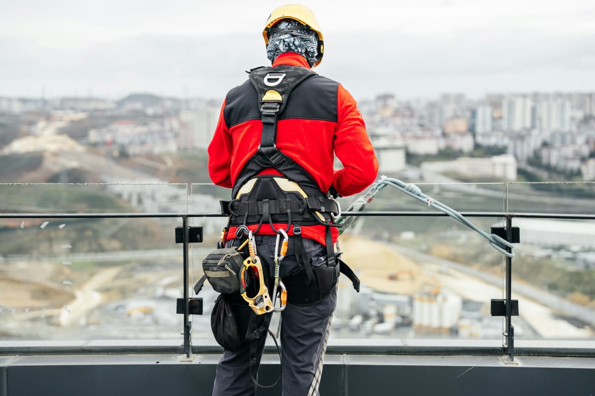 Worker in a full safety harness at the roof edge