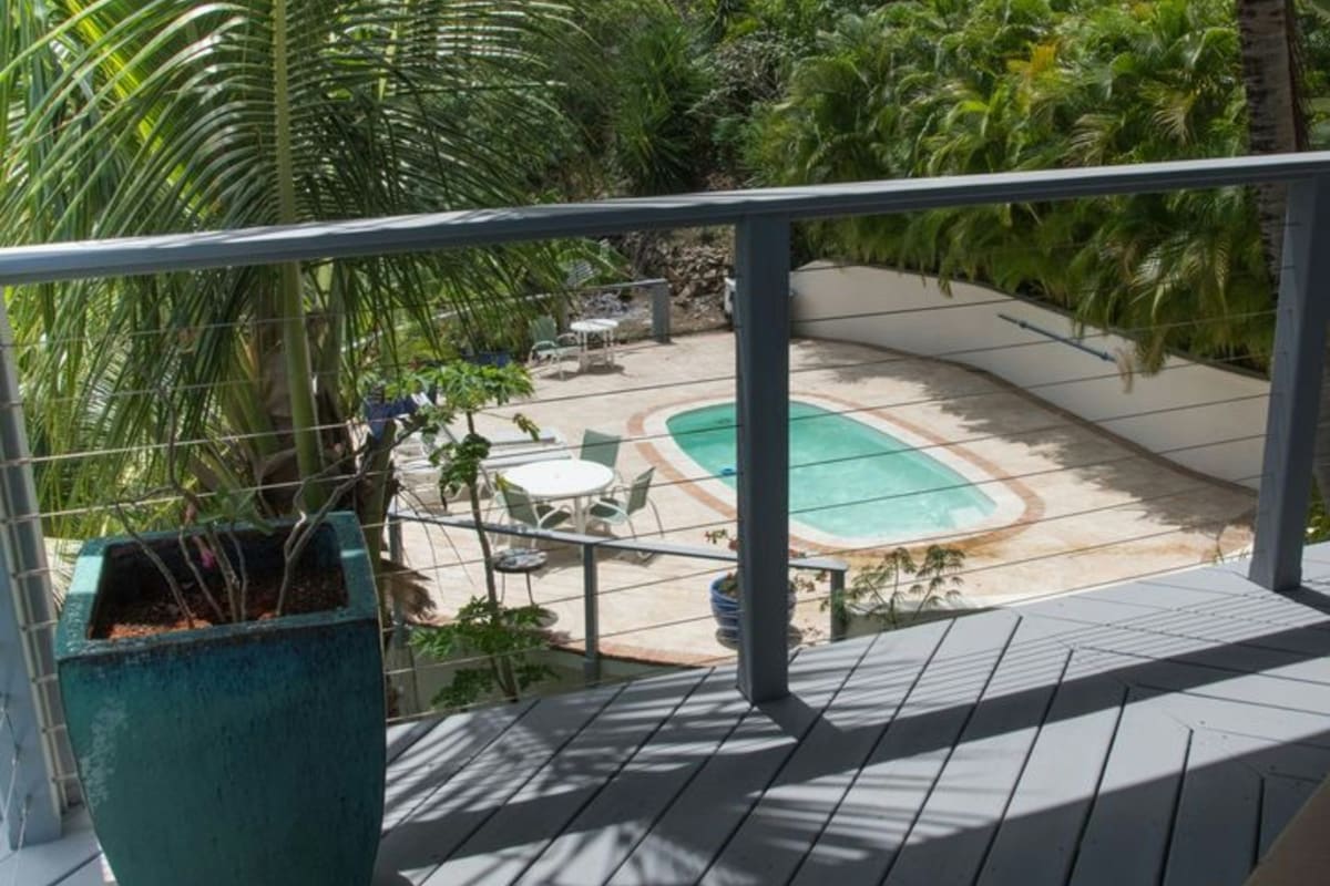 Gray composite deck with cable railing above a pool