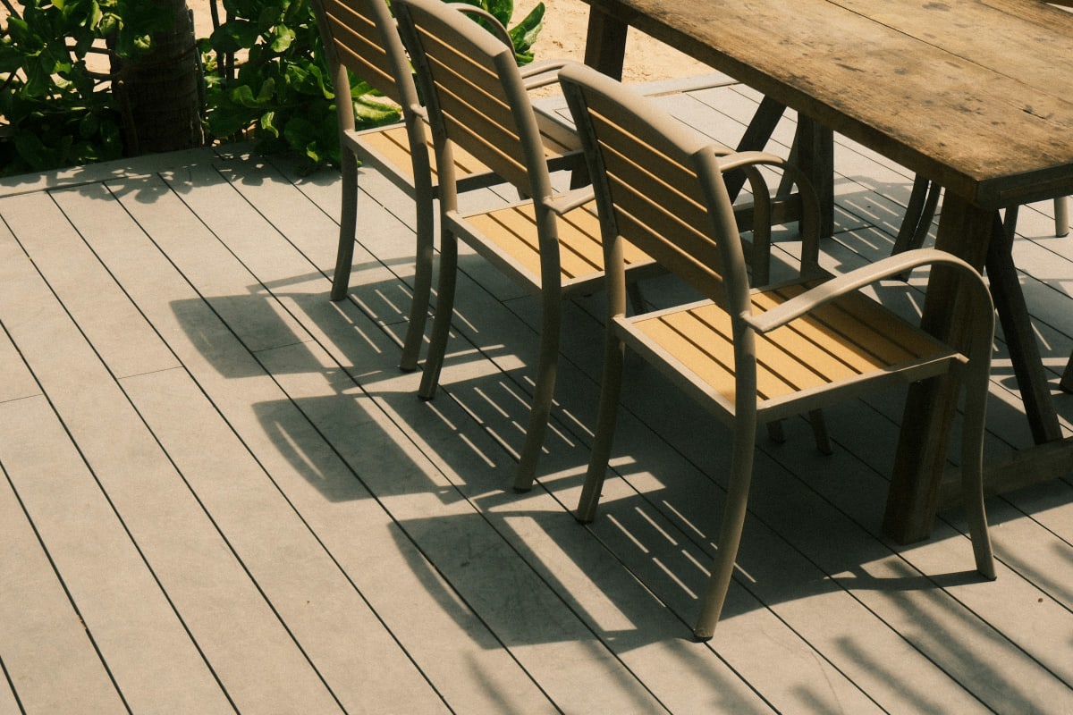 Composite deck with a wood dining table and chairs in the sun