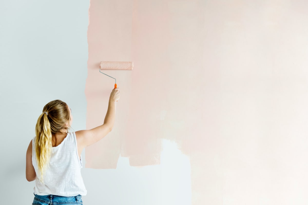 Rolling soft pink paint onto a wall
