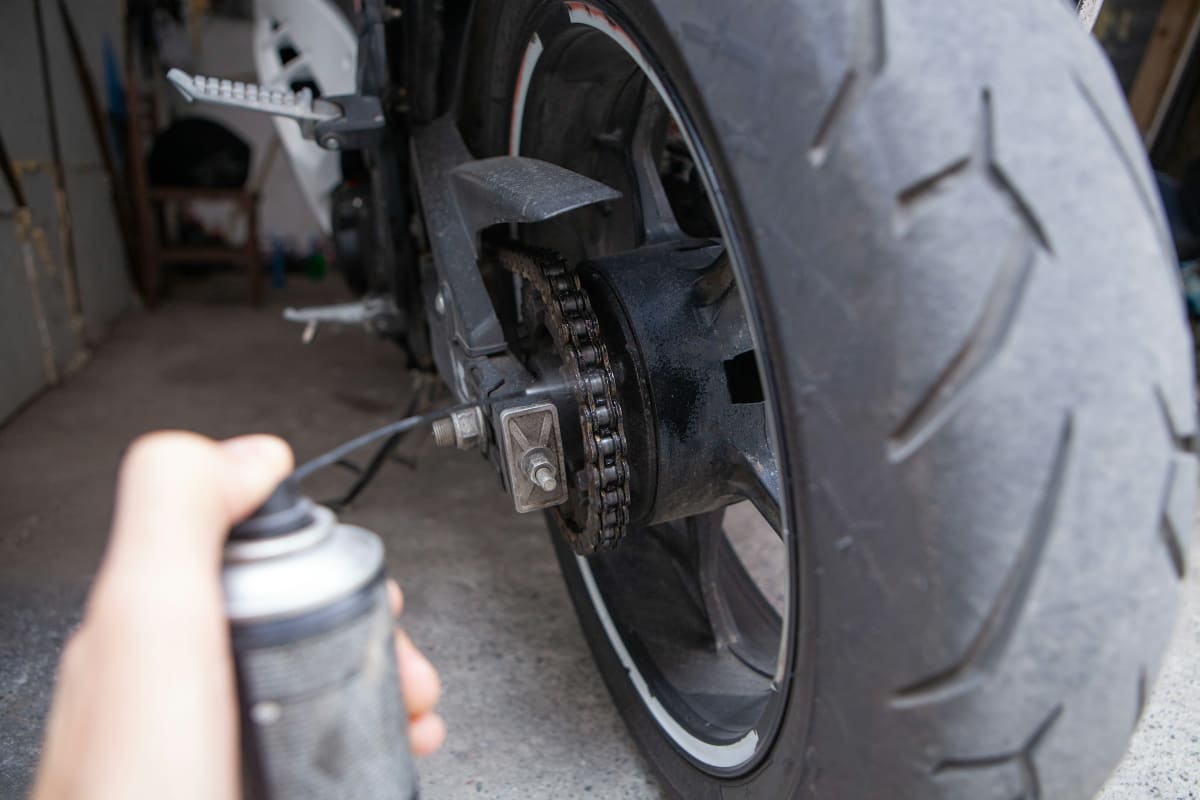 Spraying lube on a motorcycle chain