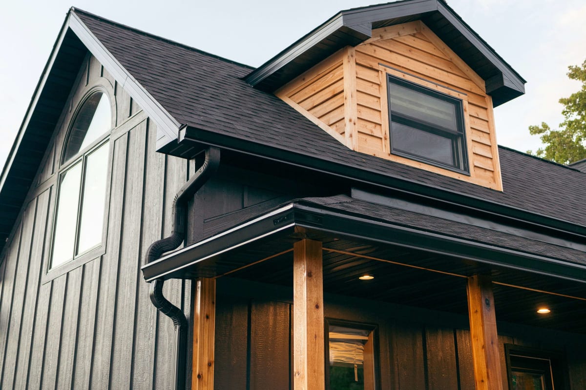 House with gray siding, a dark roof and wood trim