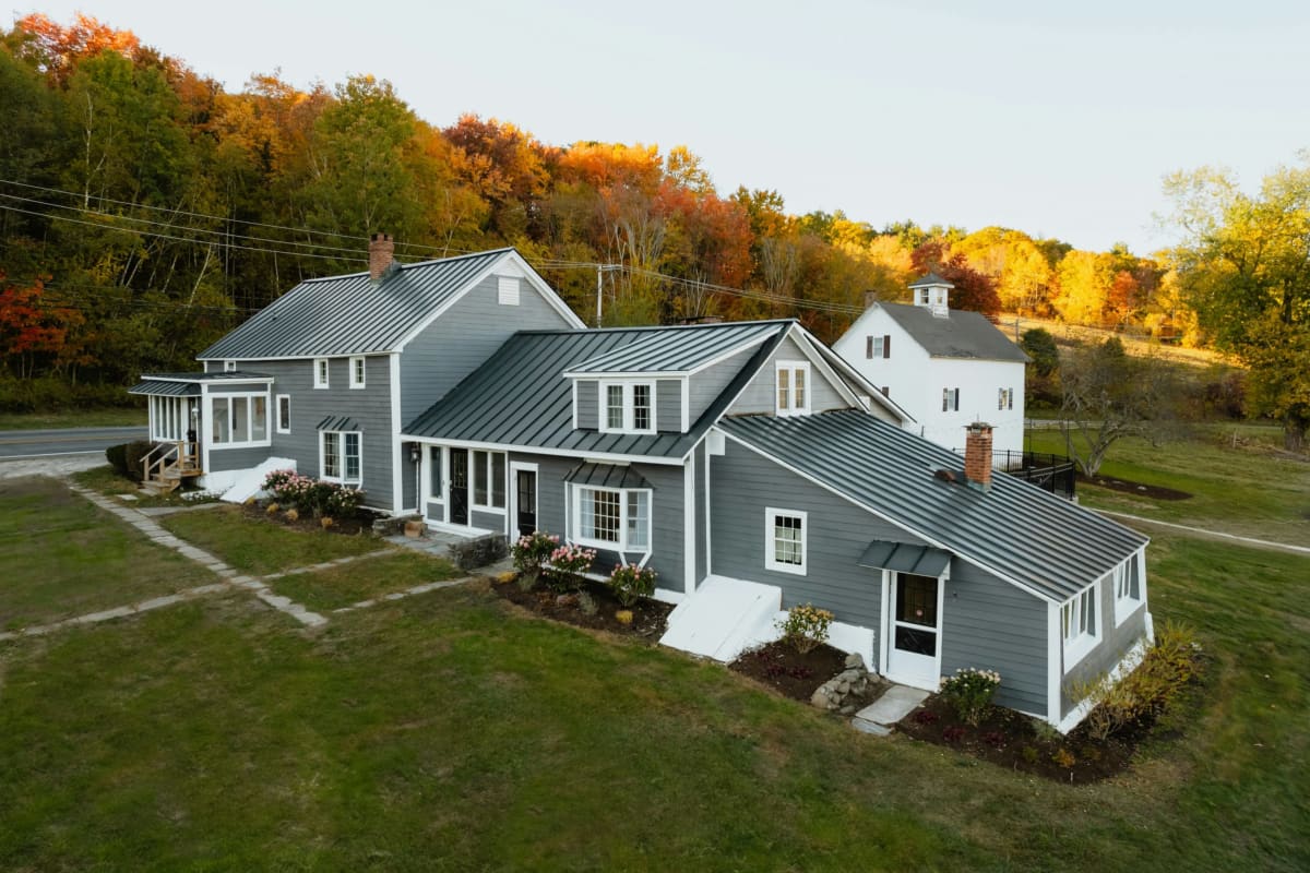 Aerial view of a gray-sided farmhouse among fall color