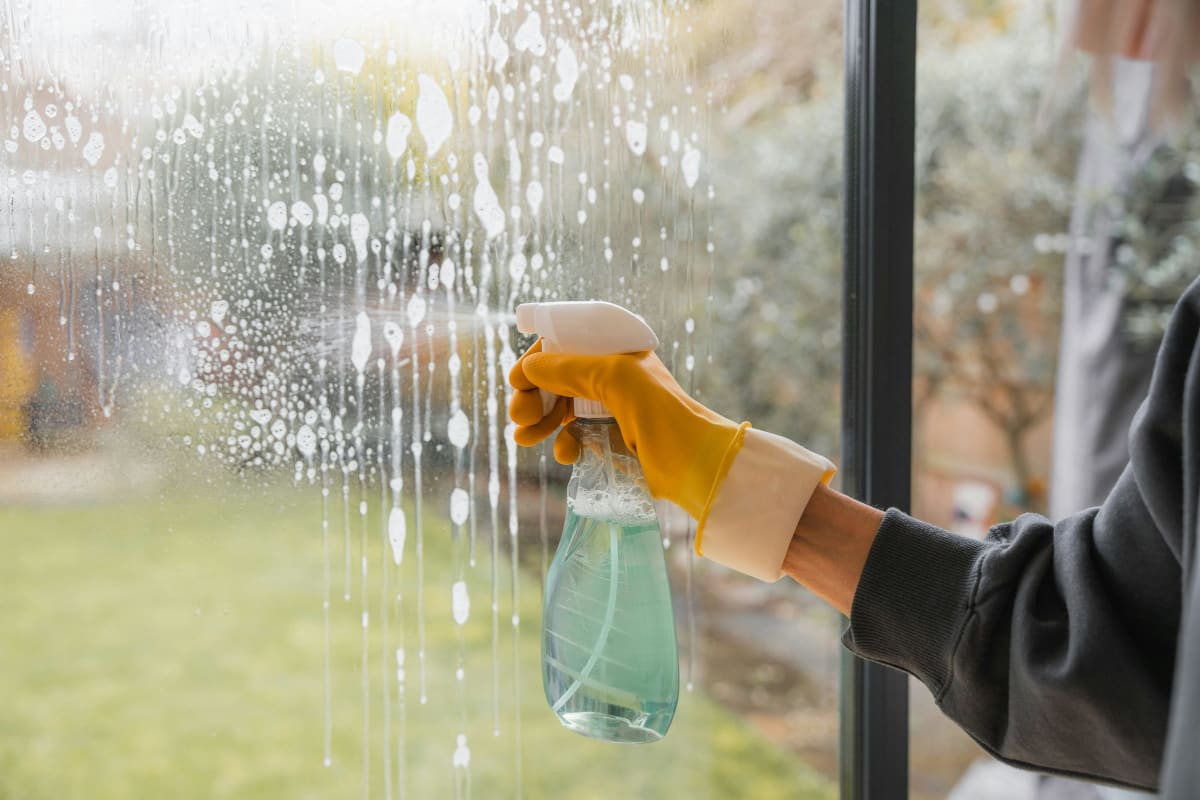 Spraying glass cleaner on a window