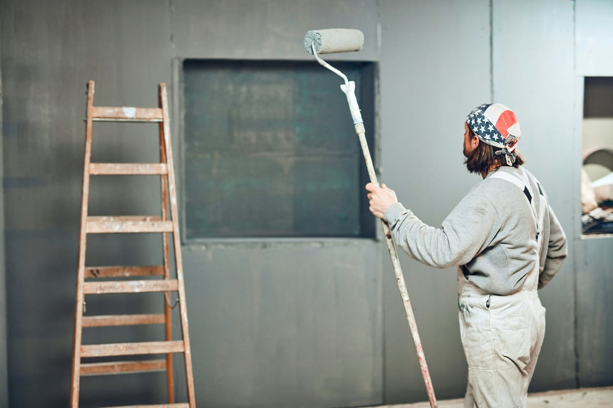 Painter rolling primer on a dark wall