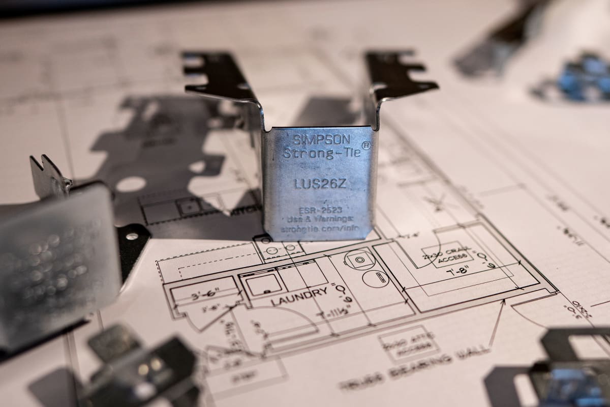 Close-up of a Simpson Strong-Tie LUS26Z joist hanger standing on house plans