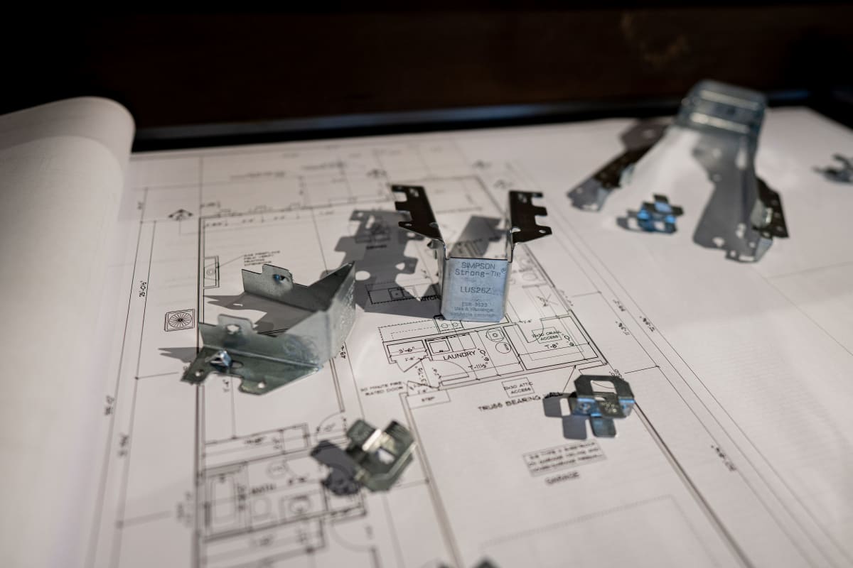 Simpson Strong-Tie hangers and connectors spread across an open set of house plans