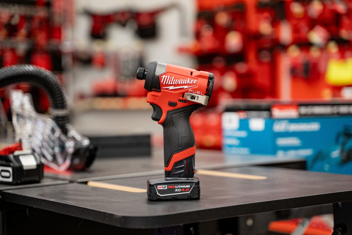 Milwaukee M12 FUEL impact driver with a REDLITHIUM battery on a workbench