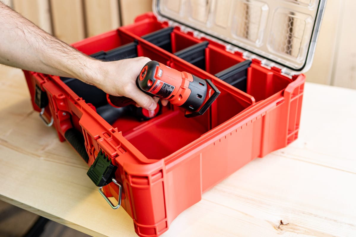 Hand placing a Milwaukee drill into an open PACKOUT organizer