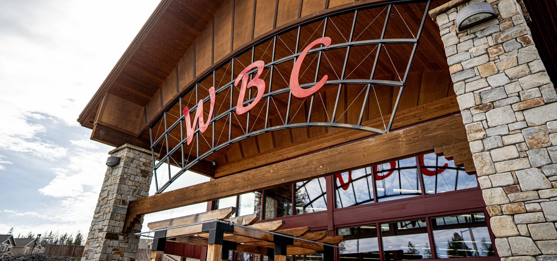 WBC lodge entrance with curved wood overhang and stone pillars