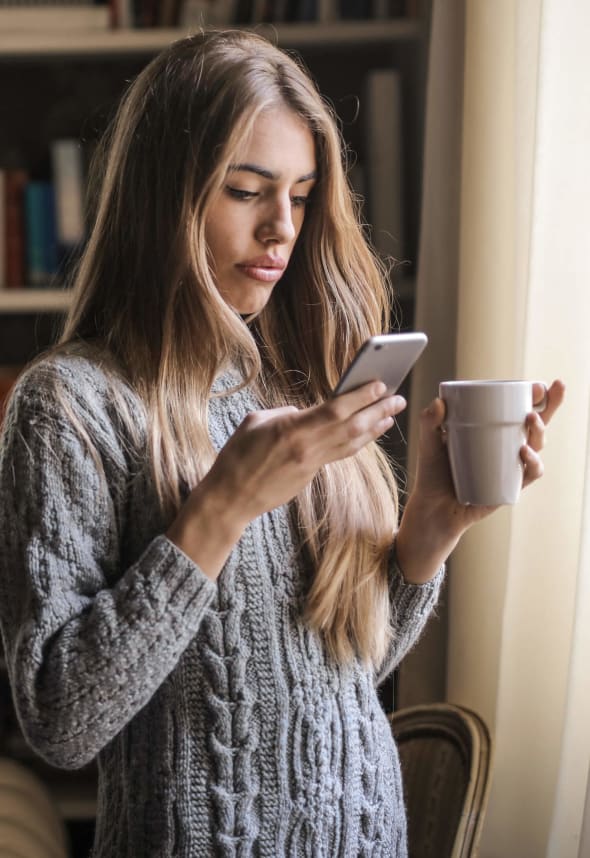 Personne utilisant son téléphone portable en prenant un café