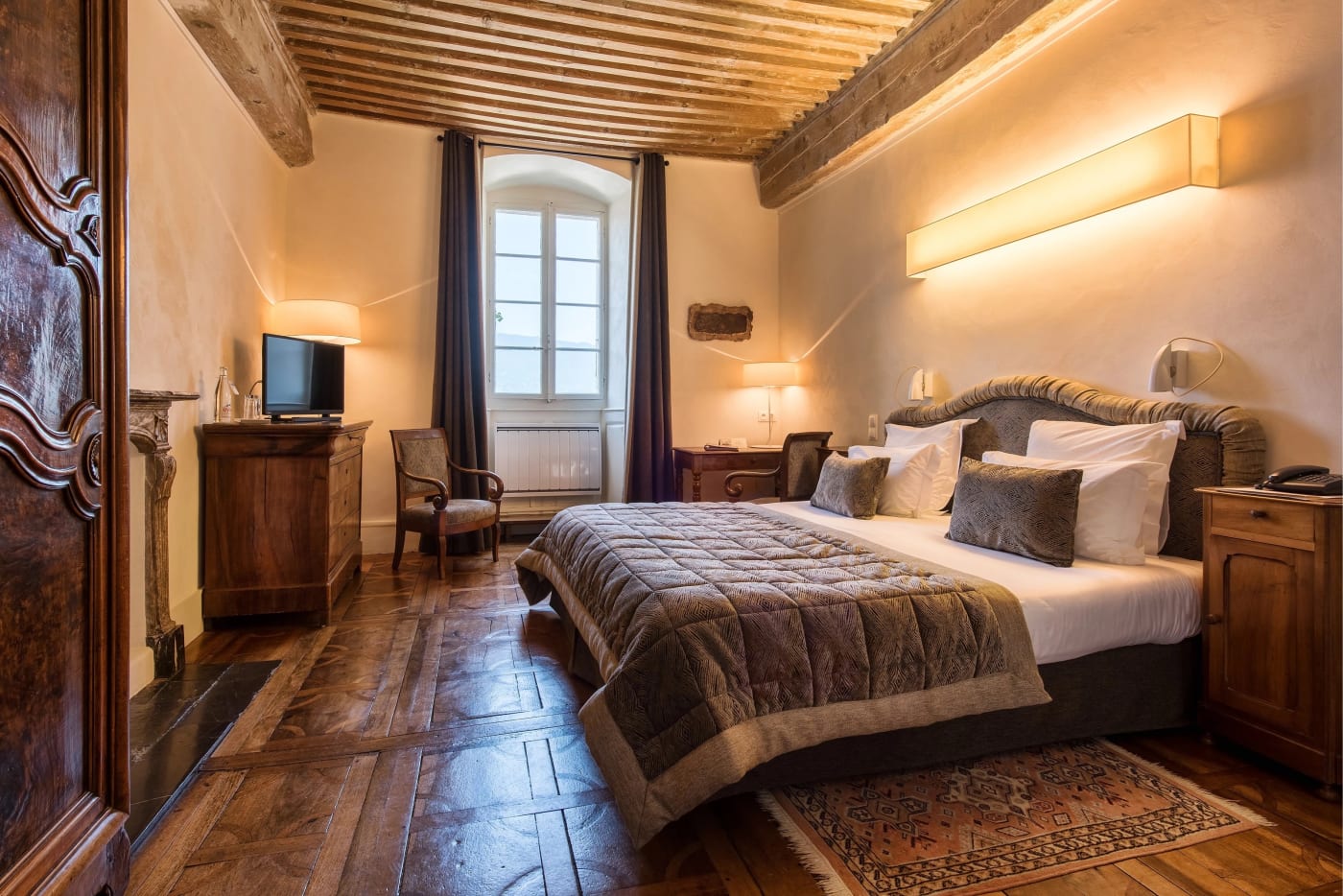 Una habitación de la Abbaye de Talloires, con techo de vigas, parqué antiguo y muebles de época