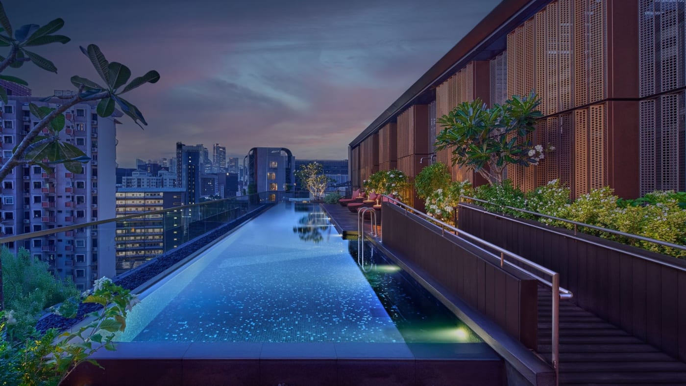 Infinity-Pool auf dem Dach des Varel Singapore bei Einbruch der Nacht mit Blick auf die Stadt