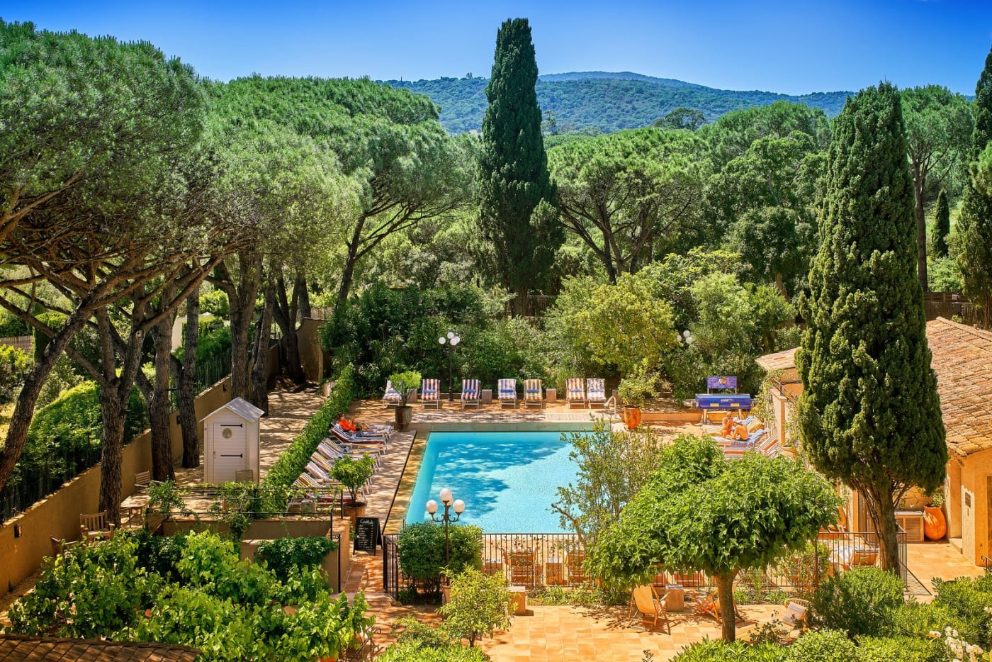 Blick von oben auf Garten und Pool des La Ferme d'Augustin, zwischen Zypressen, Pinien und den Hügeln von Ramatuelle
