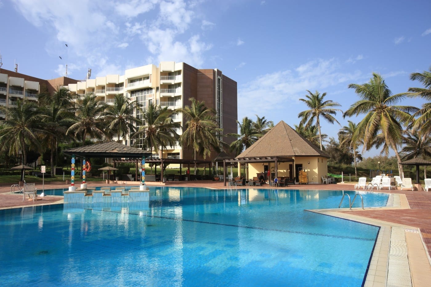 A piscina do King Fahd Palace em Dakar, cercada de coqueiros, diante da fachada do hotel