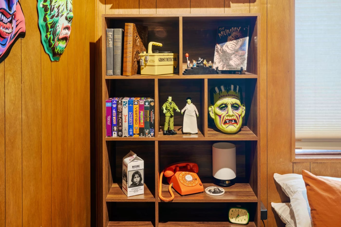 Estantería del dormitorio de la cabaña de Big Bear Lake con cintas VHS, figuras y máscaras de películas de terror