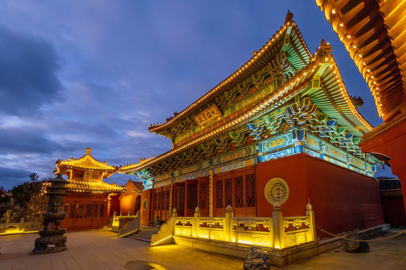 Ein rot-goldener chinesischer Tempel, bei Einbruch der Nacht beleuchtet, im Reich der Mitte von Pairi Daiza