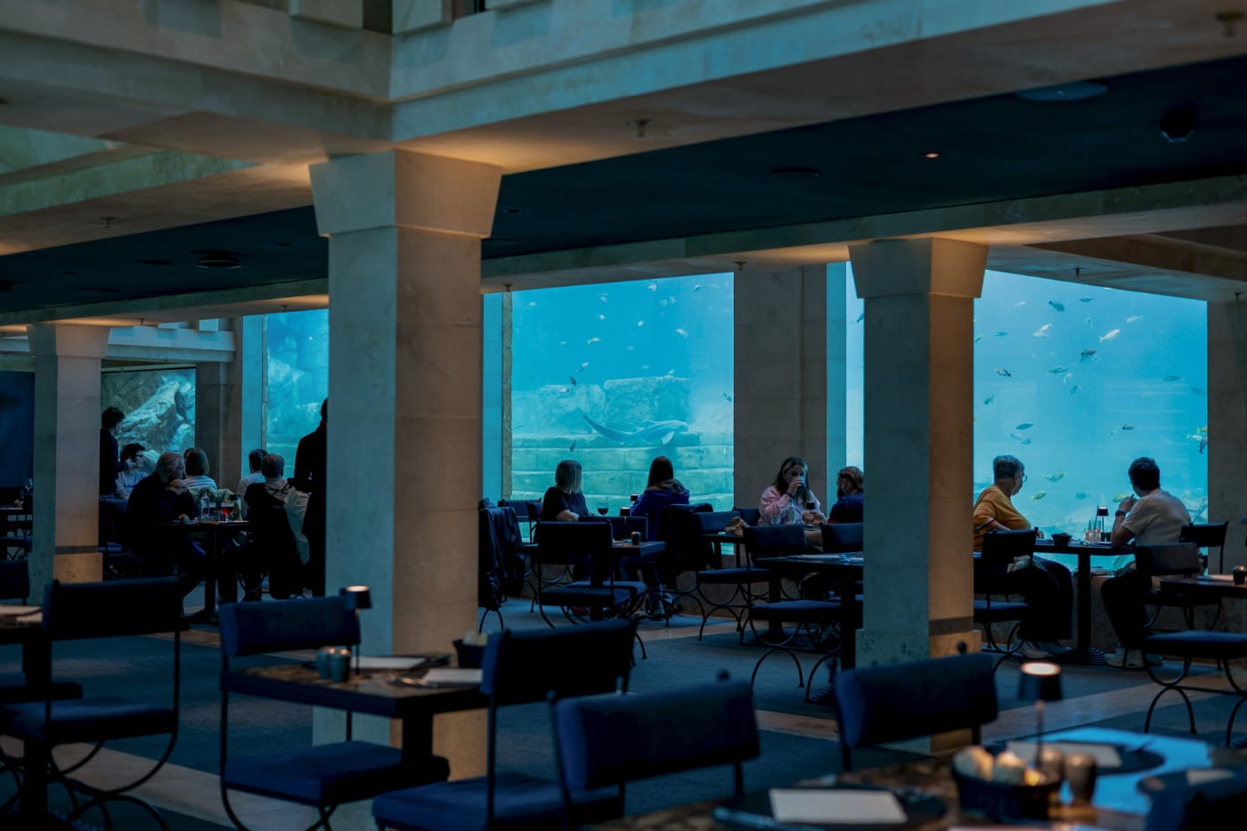Der Speisesaal des Restaurants The Abyss mit großen Glasfronten zu einem Haibecken