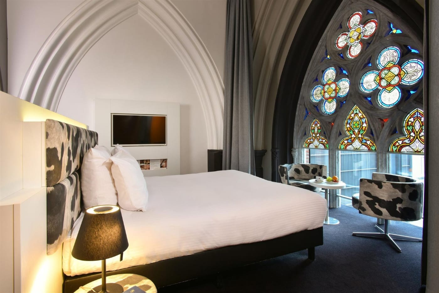 Ein Zimmer im Martin's Dream in Mons unter einem Kirchengewölbe, mit einem großen bunten Kirchenfenster