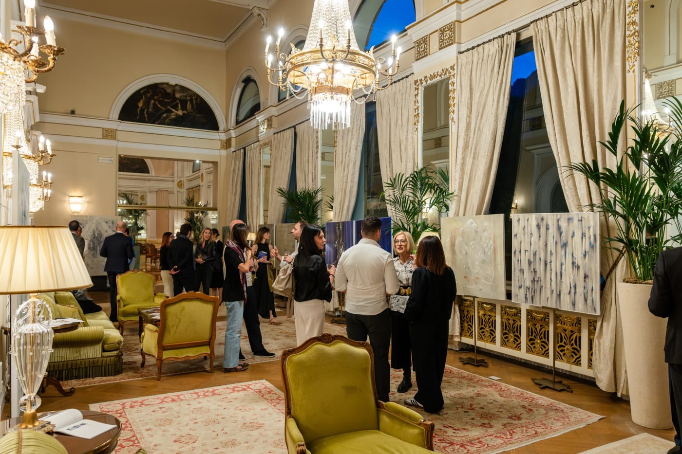 Gäste der Vernissage der Ausstellung Les Incarnées in einem Salon des Palace Merano