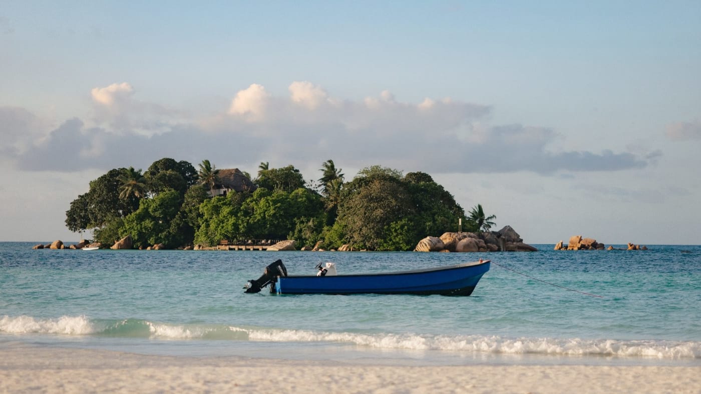 Barque devant un îlot boisé au large de Praslin, aux Seychelles