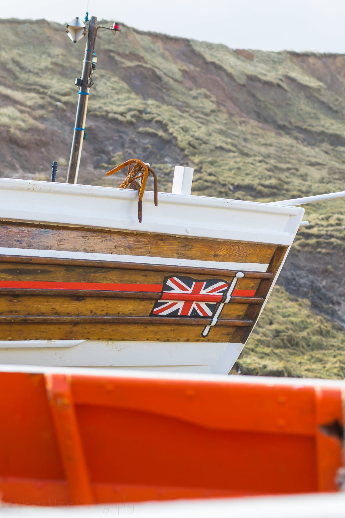 Union Jack painted on a fishing boat beneath coastal cliffs