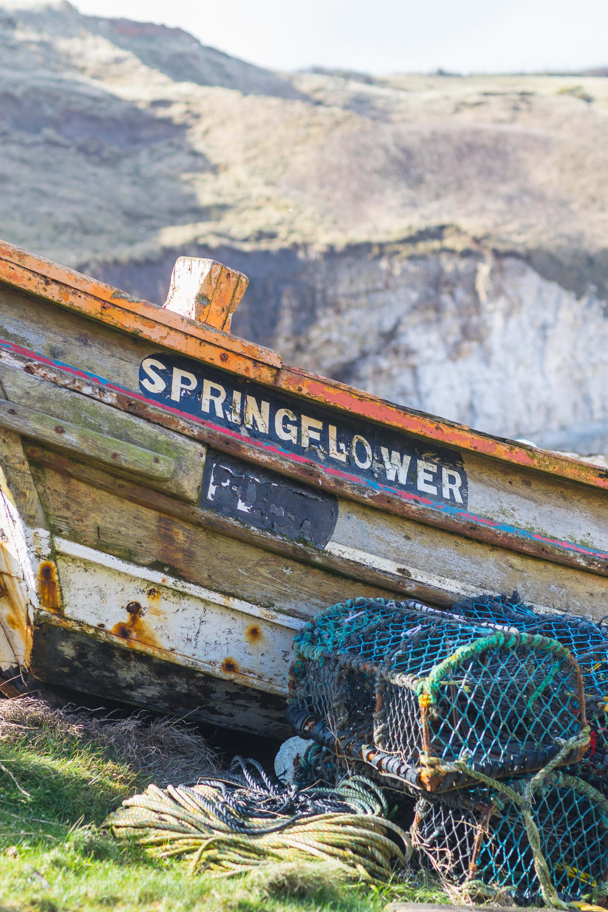 Weathered Springflower fishing boat with lobster pots on shore